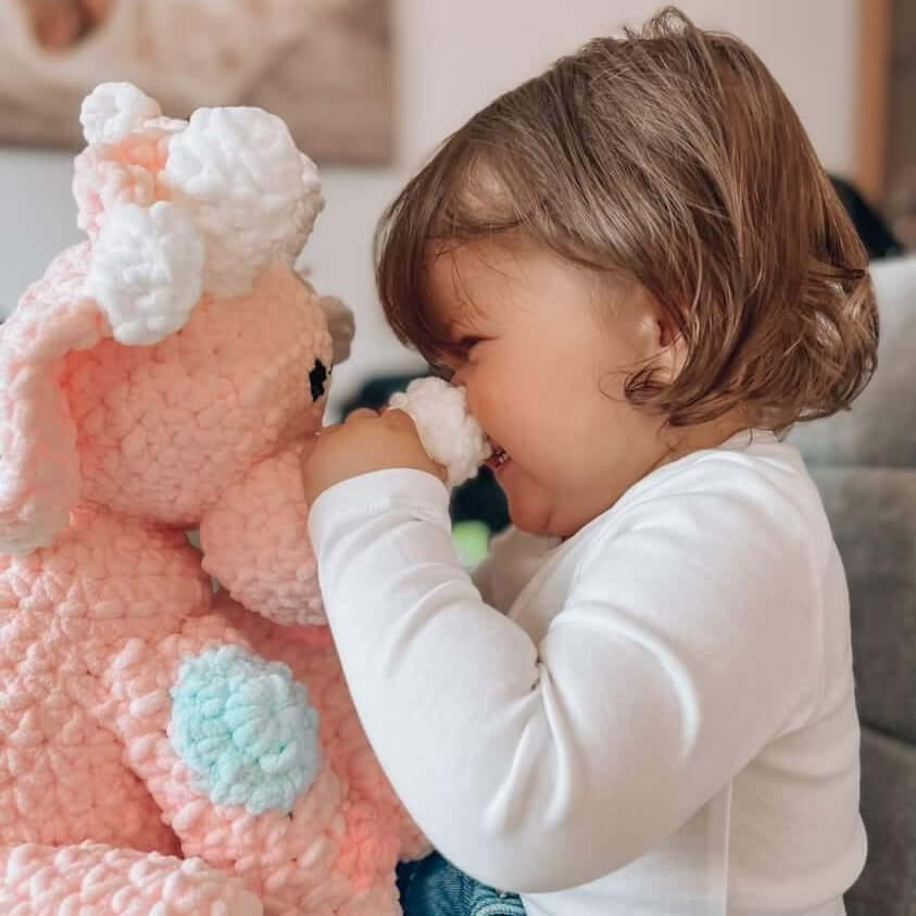 Toddler smiling with pink dinosaur plushy soft toy unique baby gift