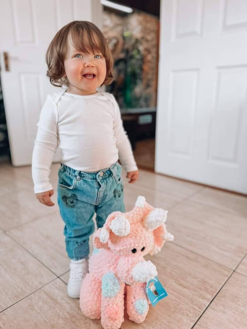 Toddler smiling with pink dinosaur plushy soft toy unique baby gift