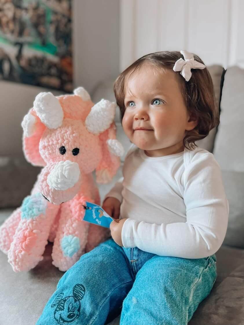 Toddler smiling with pink dinosaur plushy soft toy unique baby gift