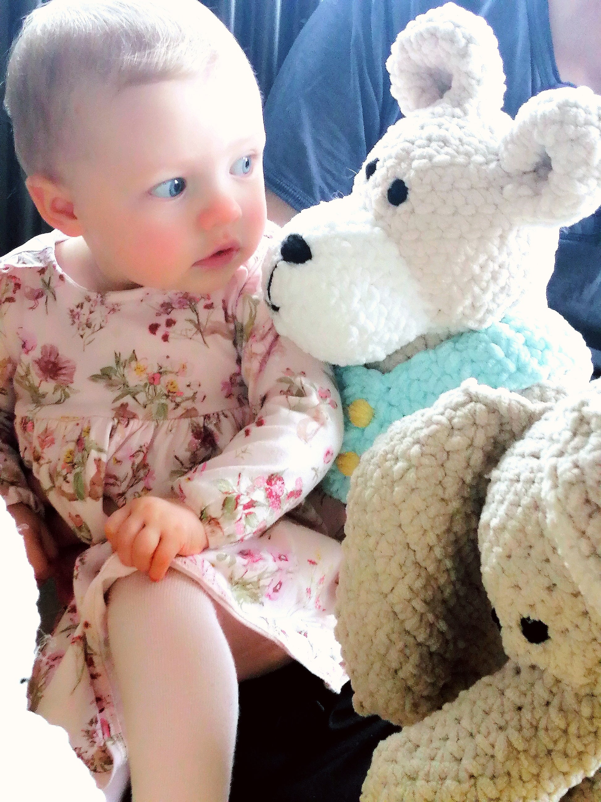 Baby girl looking at Teddy bear soft toy, handmade baby gift made in Ireland Wonky Woolins. Unique baby gift
